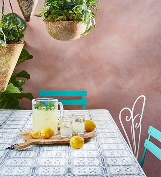 pink plastered wall with outdoor table in white with blue stencil tile effect