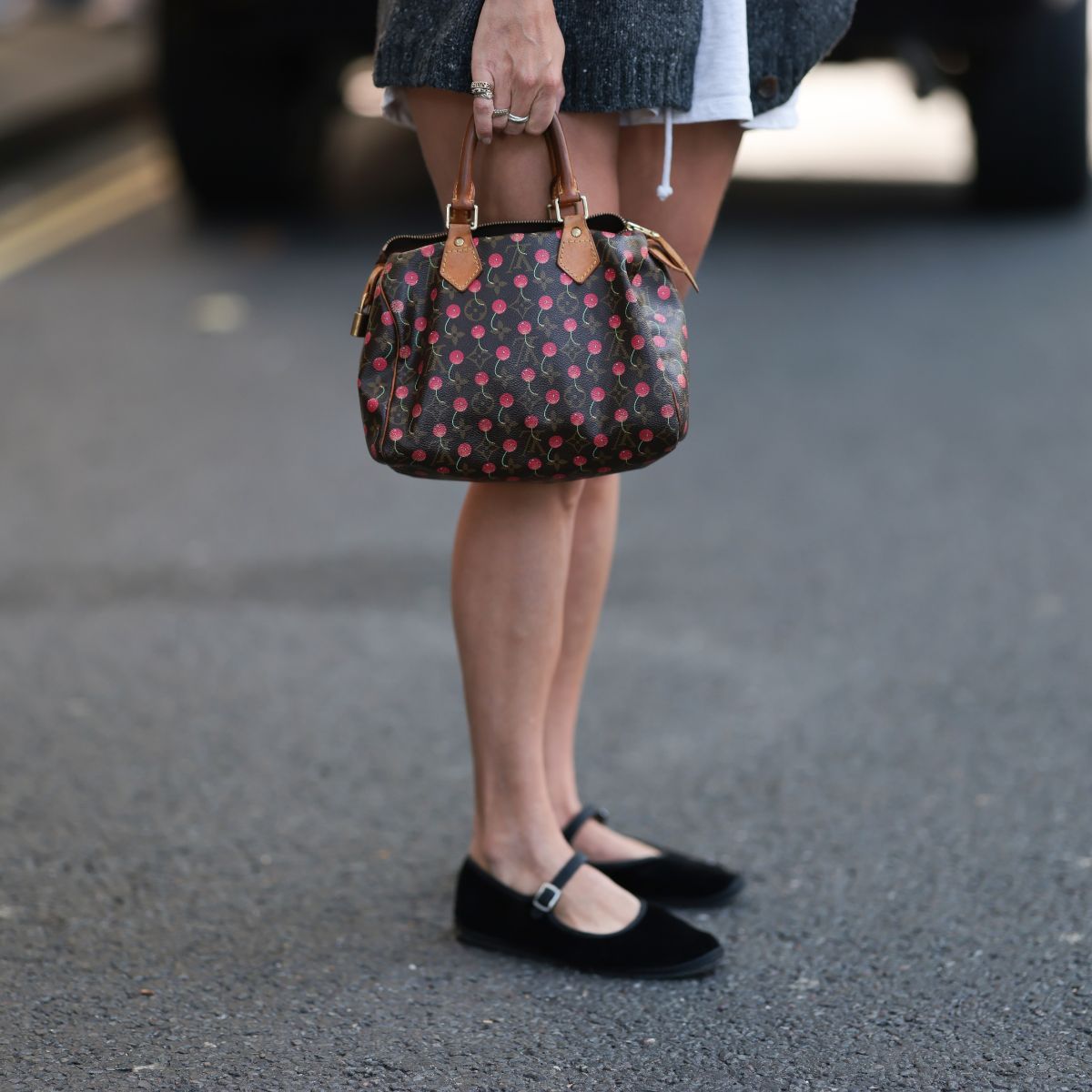 a woman wearing black ballet flats and a louis vuitton bag