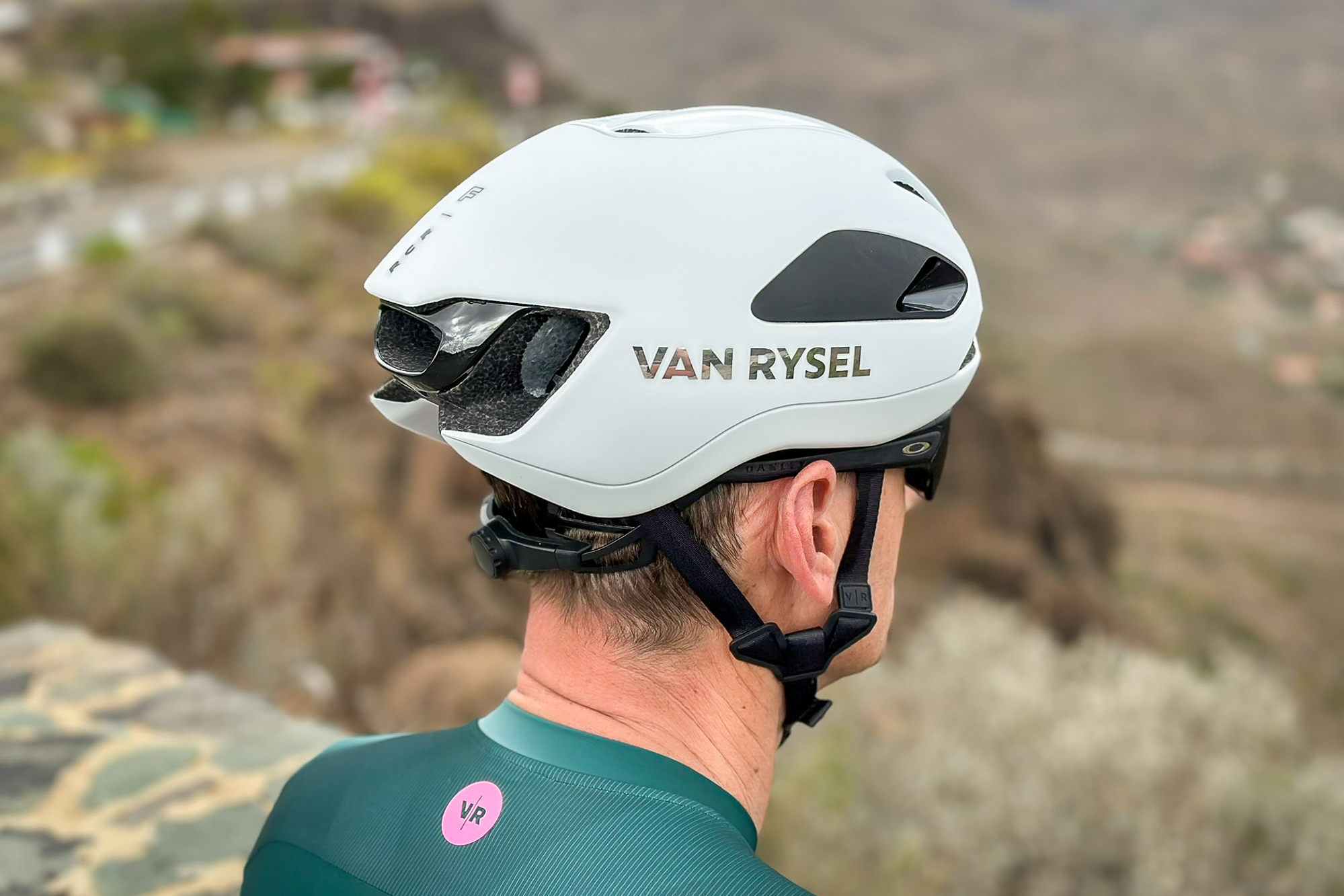 Side view of a man wearing a white helmet, sunglasses and a green jersey