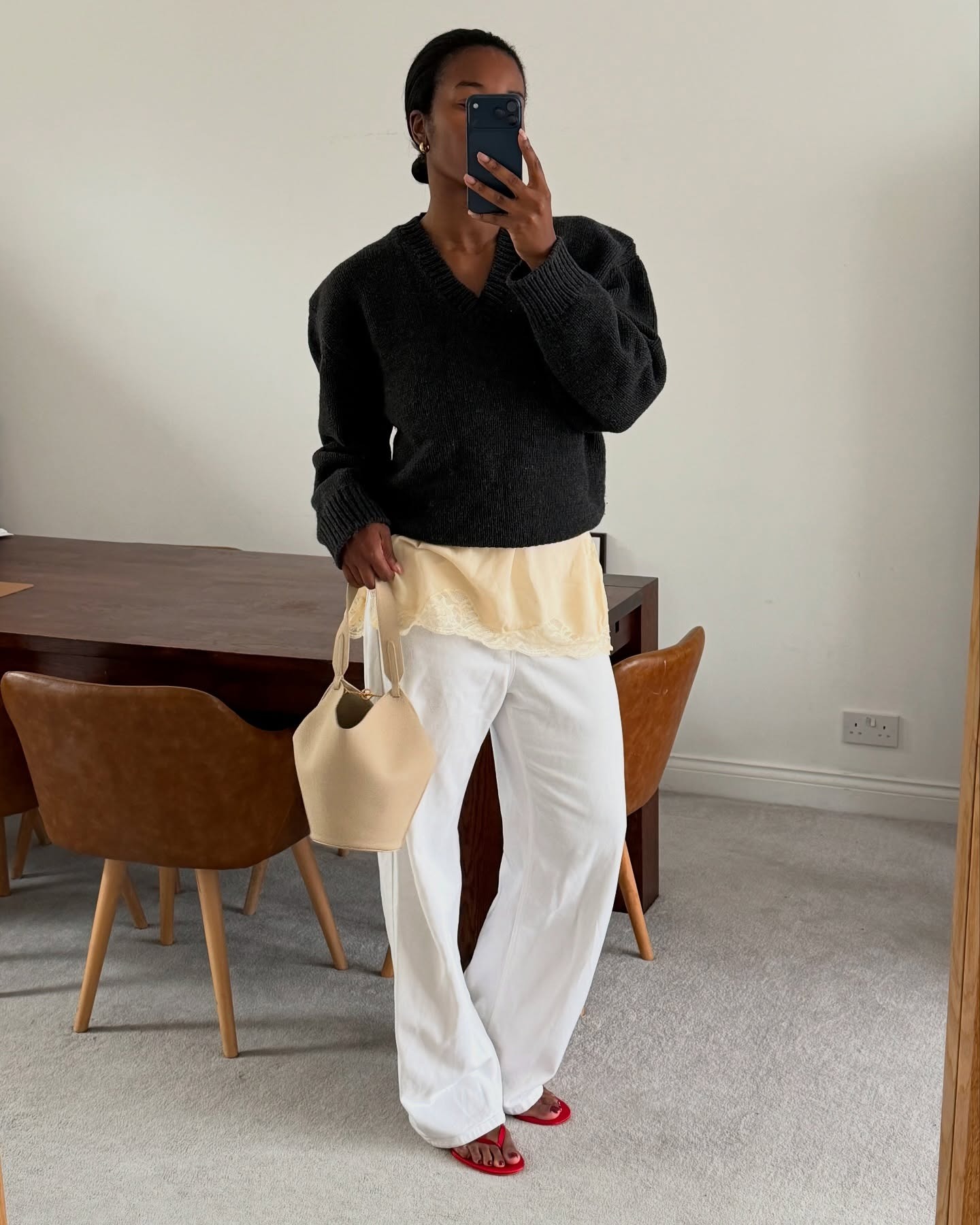 Woman in black sweater, white jeans, and yellow lace-trim top.