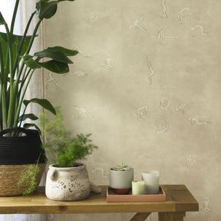Side table with plants and candles next to wall with wallpaper