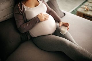 A pregnant woman drinking a glass of milk