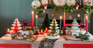 Christmas table dressed with red and green paper Christmas trees to create a centrepiece