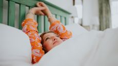 Woman lying in bed without mouth taping, arms stretched over head