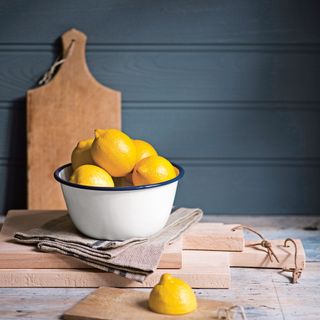 Metal bowl of lemons on stack of chopping boards
