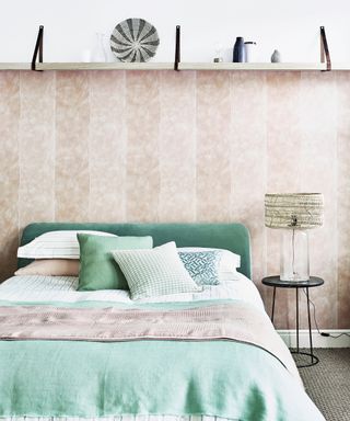 A bedroom with neutral textured walls and mint green bed linen