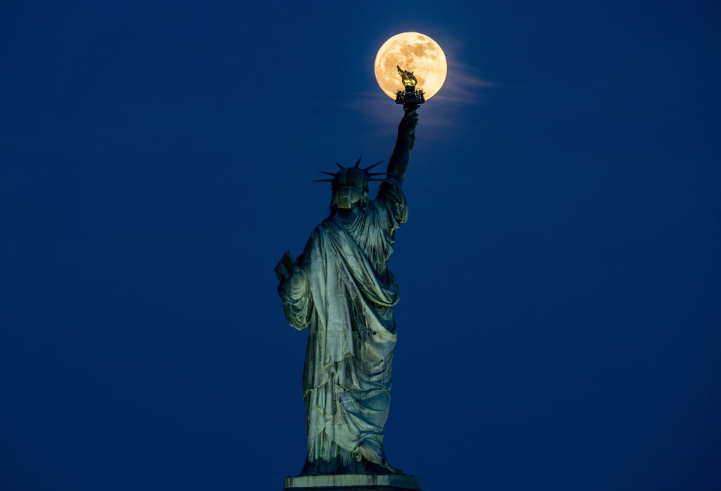 The Flower Moon rises behind the Statue of Liberty in New York City, United States on May 22, 2024.