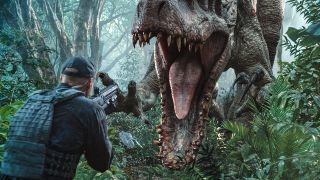 Scene from the movie Jurassic World. Member of the Asset Containment Unit (ACU) holding a gun whilst a large dinosaur (Indominus rex) is charging at him with claws raised and teeth bared.