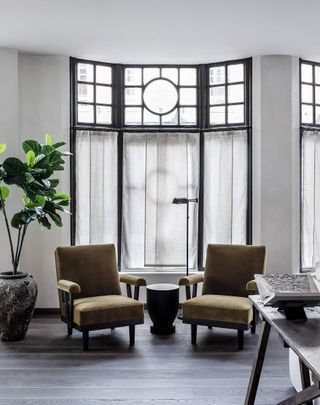 A sitting area with two leather chairs and a round coffee table by a large window.