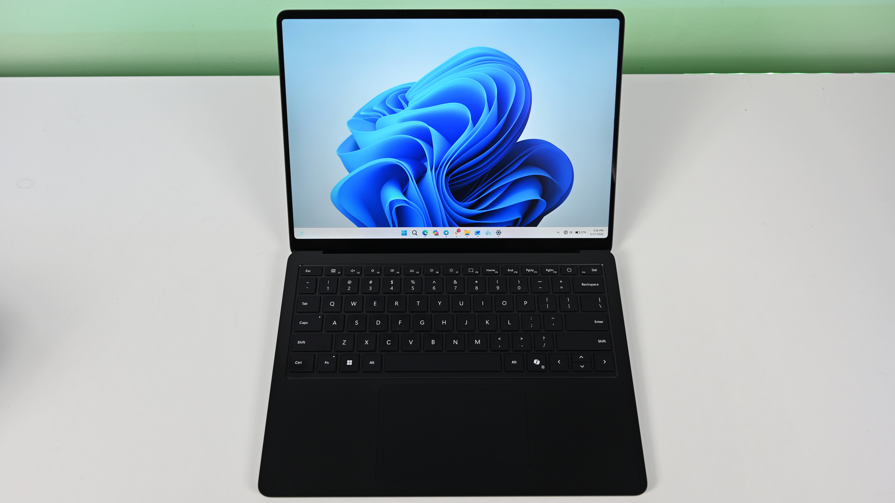 Surface Laptop for Business 8th Edition, with a black keyboard and a modern design, displaying a blue abstract swirl on its screen, set against a light gradient background.