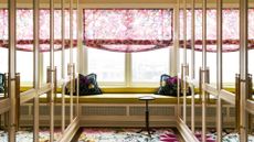 A luxe walk-in wardrobe with mirrored doors, in-built seating, and a floral rug