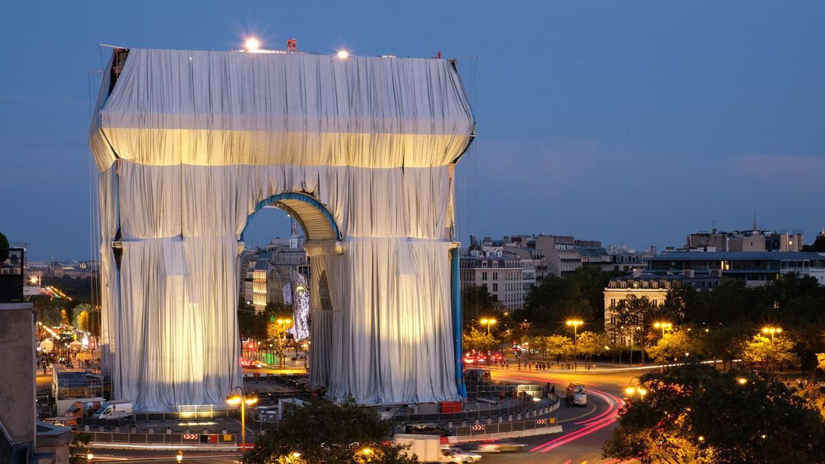 A photo of the wrapped Arc de Triomphe at night time. 