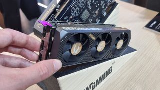 The Zotac Gaming RTX 5060 Low Profile on a display stand, with a hand for scale