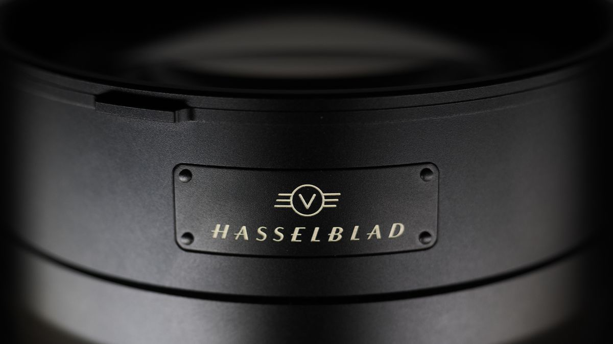 Hasselblad XCD 35-100E lens on a wooden surface in a moodily lit environment