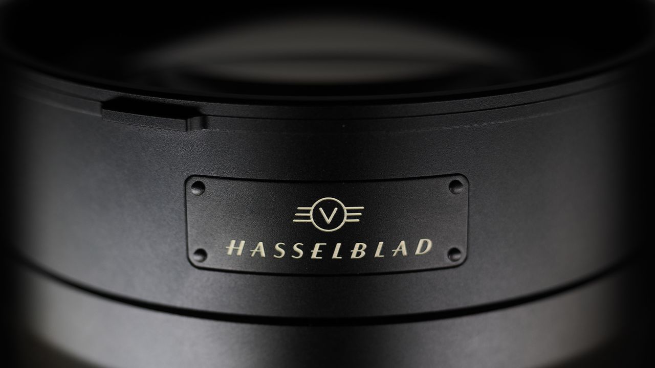 Hasselblad XCD 35-100E lens on a wooden surface in a moodily lit environment