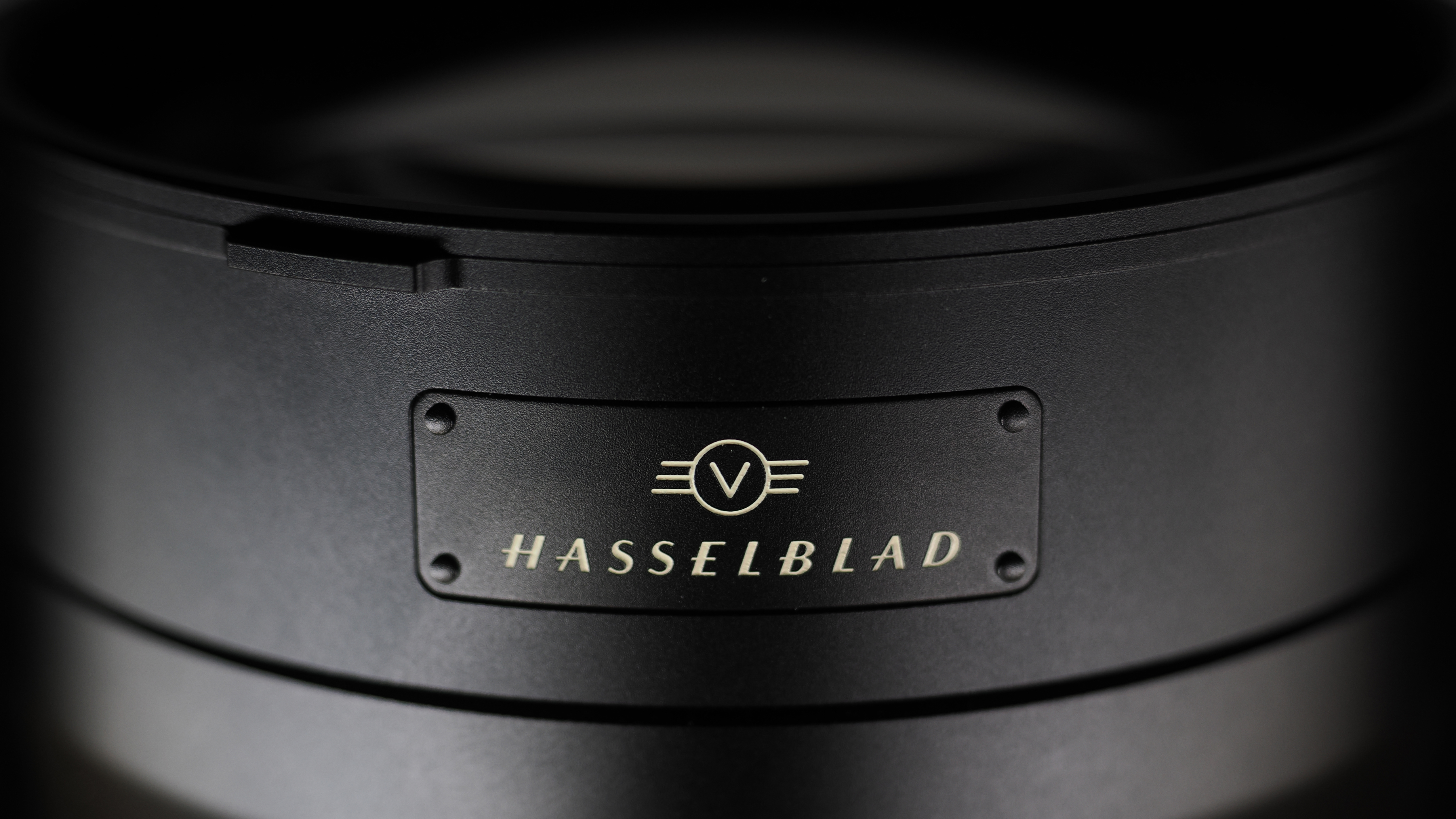 Hasselblad XCD 35-100E lens on a wooden surface in a moodily lit environment
