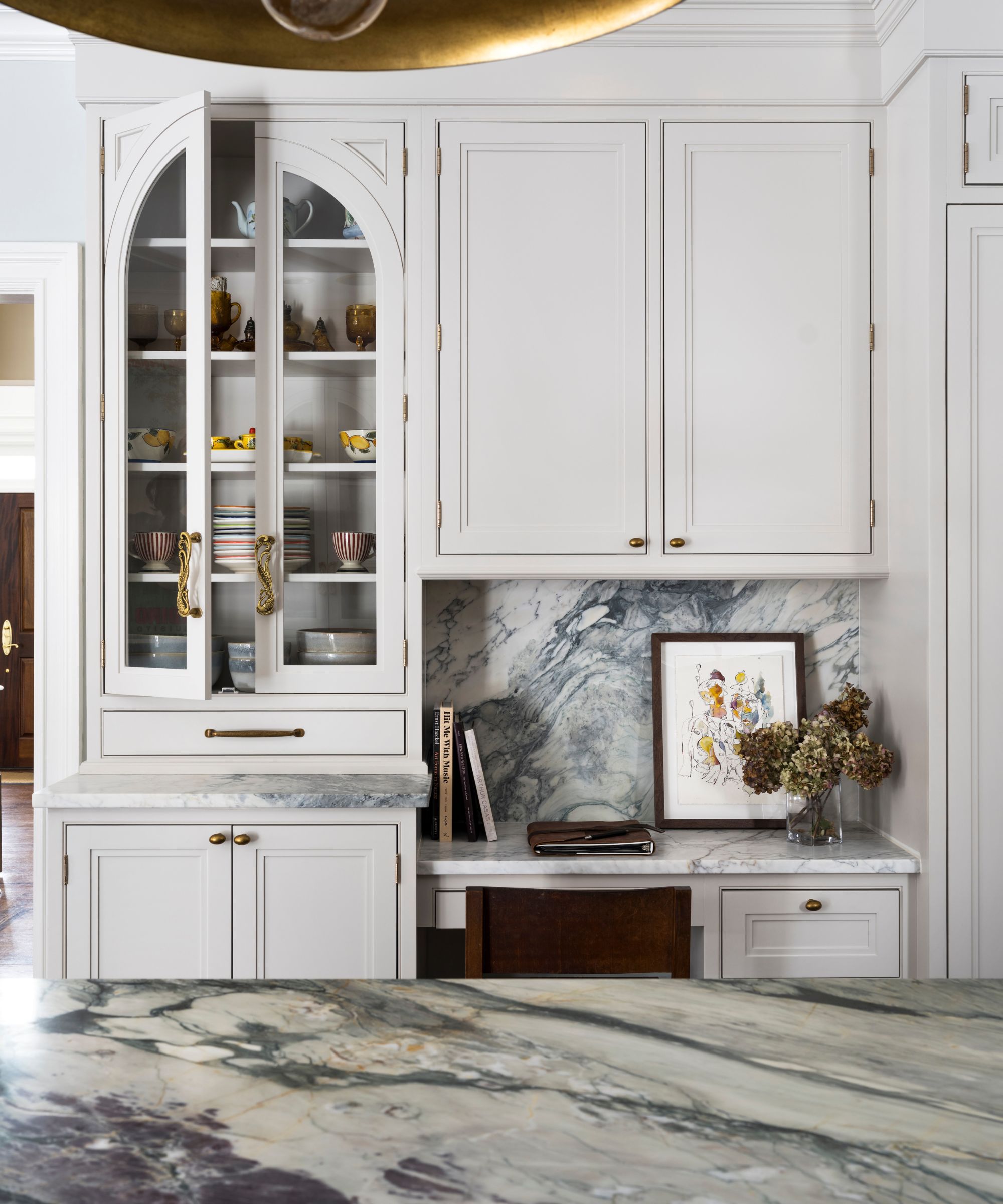 White shaker kitchen cabinets with brass hardware and marble countertops