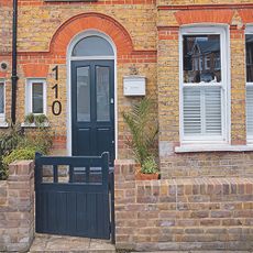 House with navy front door and stone wall.