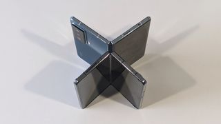 En vikbar Honor Magic ligger halvt öppnad på sidan på ett vitt bord med en halvt öppnad Samsung Galaxy Z Fold 4 placerad under den.