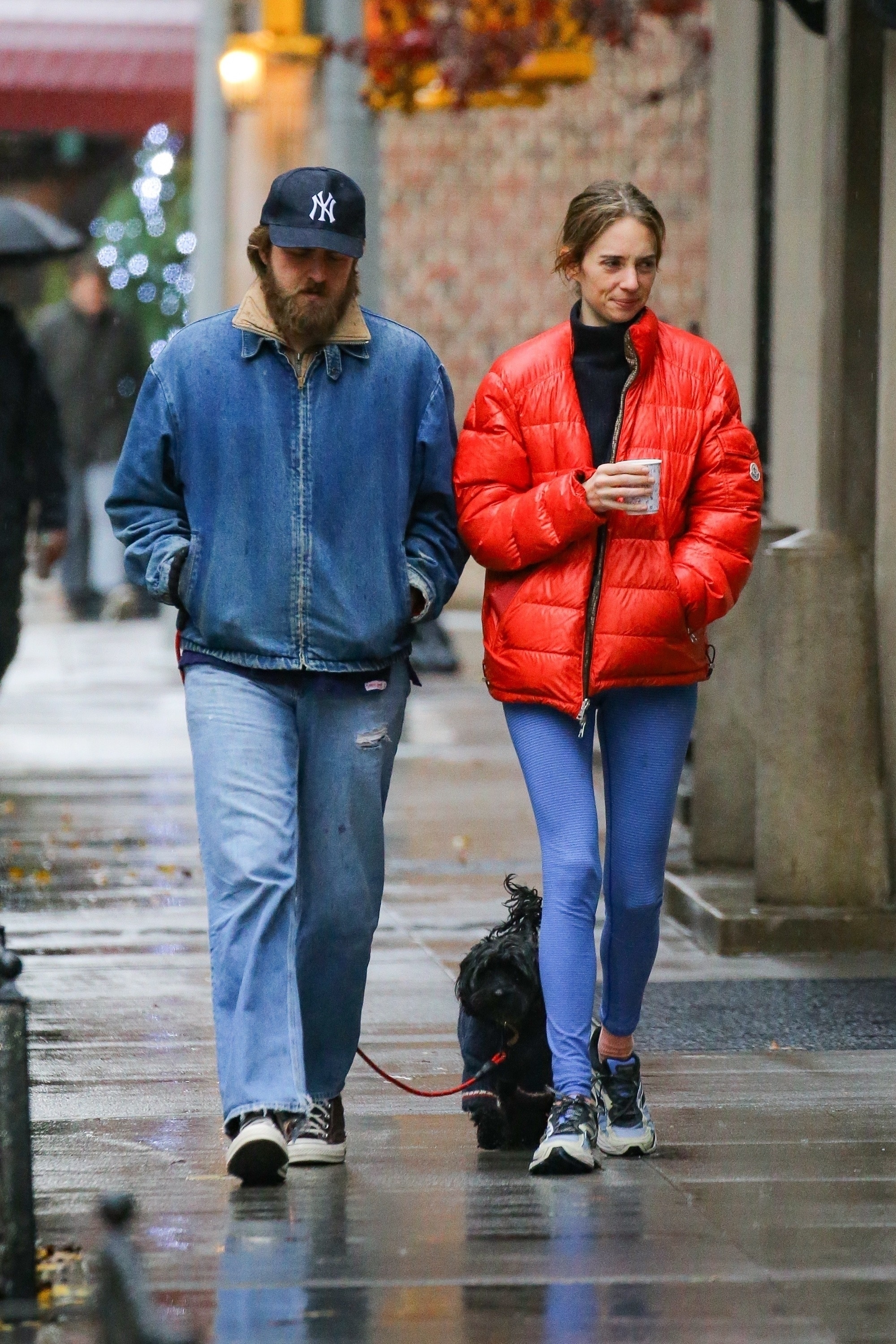 Maya Hawke wears a red Moncler puffer jacket with blue leggings and sneakers in NYC