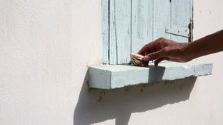 Hand placing a sea shell on window sill