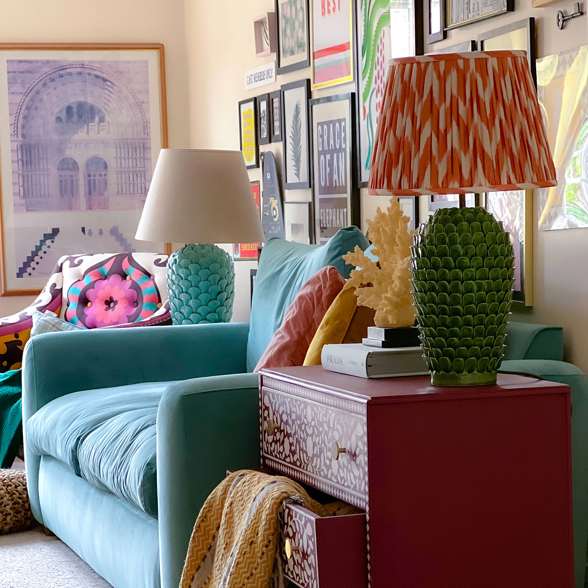 Living room with colourful gallery wall and teal sofa with a lamp on either side, one turquoise base with white shade, the other with a green base and orange chevron patterned shade