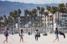 Volunteers pick up litter on a windy Venice Beach as part of an Earth Day cleanup event with the Ecological Servants Project on April 22, 2022 in Venice, California