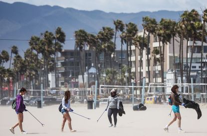 Volunteers pick up litter on a windy Venice Beach as part of an Earth Day cleanup event with the Ecological Servants Project on April 22, 2022 in Venice, California