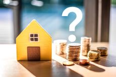 Hidden expenses of homebuying concept. Model wooden house sits next to a stack of coins, over which is a question mark. 