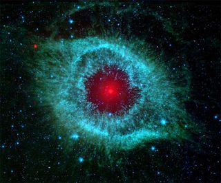 A white dwarf glows red at the center of a shimmering cloud of gas and dust in the Helix nebula, located 700 light-years away in the constellation Aquarius.
