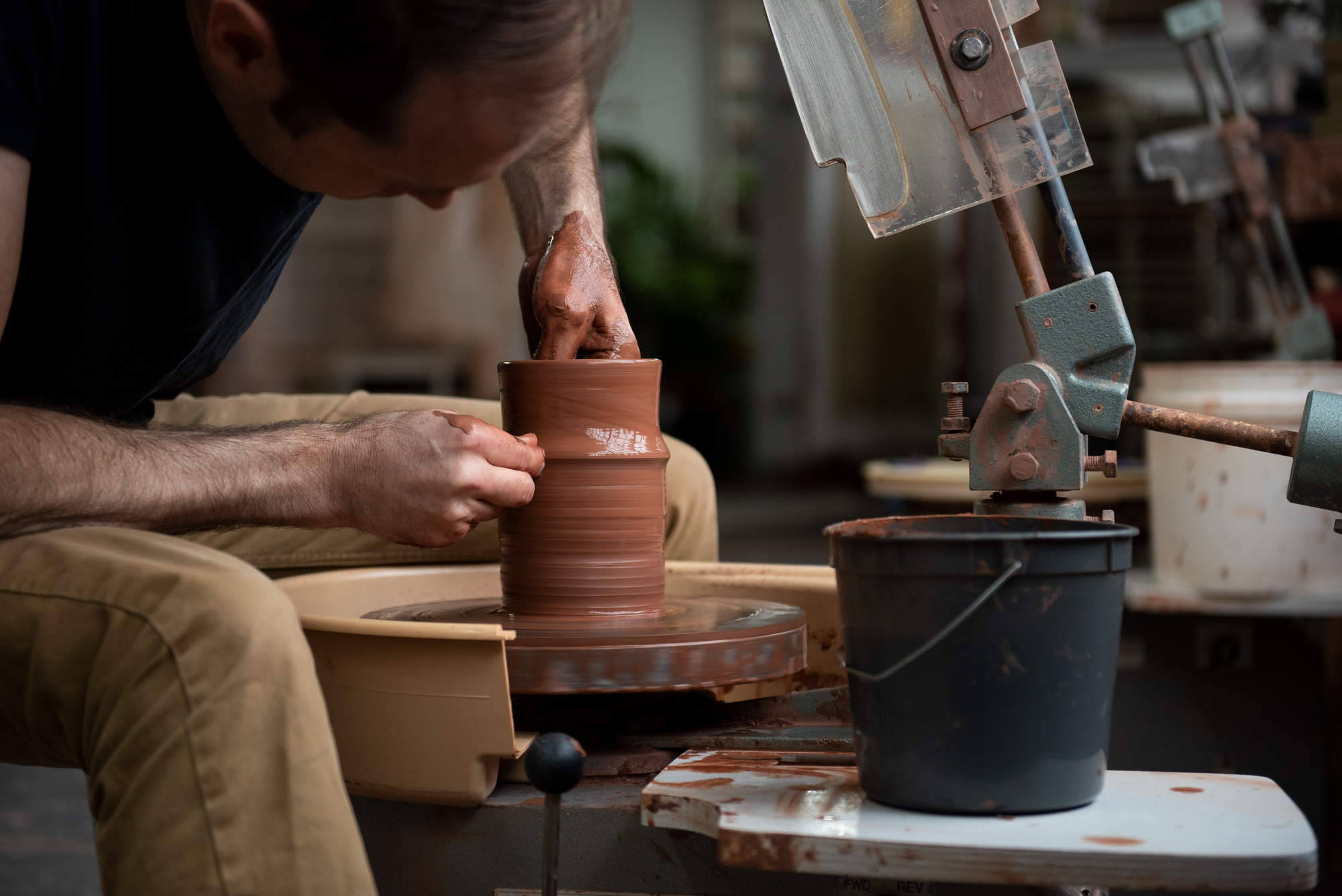 Image of Jono Pandolfi sitting at a pottery wheel making what appears to be a bowl or the beginning of a dish.