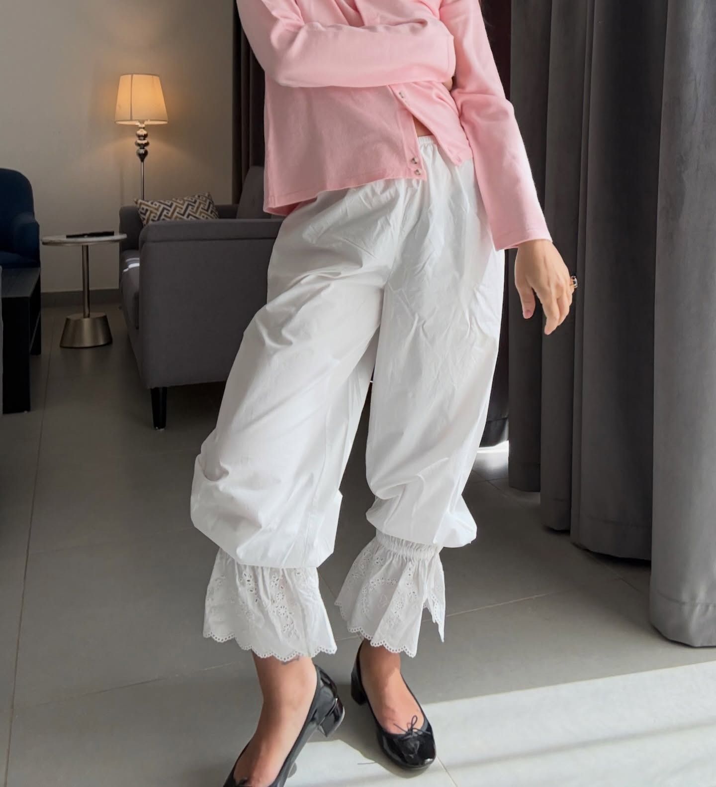 a woman wears white cropped trousers.