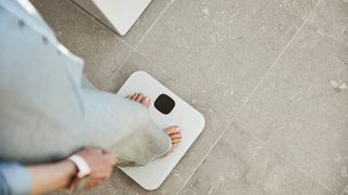 A woman stands on the Fitbit Aria Air