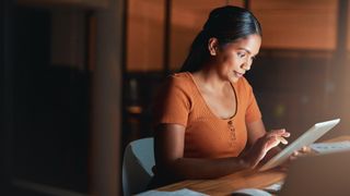 Young woman sitting alone using a tablet