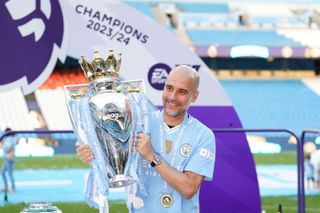 Manchester City manager Pep Guardiola holds the Premier League trophy, 2024