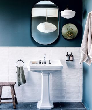 bathroom with dark green walls, white tile splashback, white basin and black mirror
