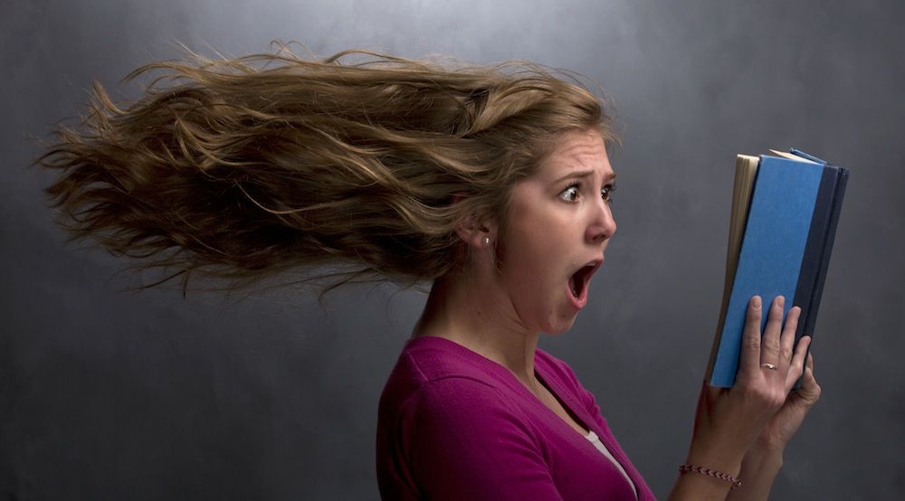 A girl shocked at a book she&#039;s reading.