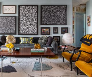 living room with grey walls, grey sofa, yellow accent chair and gallery wall above sofa