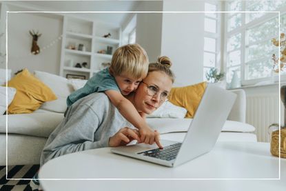 Mum looking at laptop while son leans over her shoulder to press a button