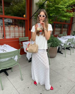 Woman in white lace skirt, graphic t-shirt, and red shoes