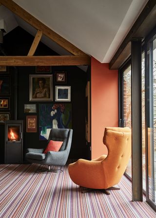 modern living room with orange walls, log burner and gallery wall stripe carpet