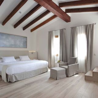 Font Santa Hotel Room with white walls, wooden beams in the ceiling, and beige furniture and upholstery.