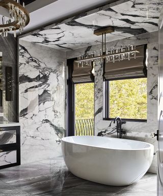 A black and white marble bathroom with a standing tub