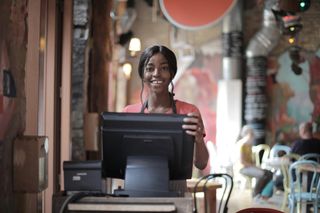  Une femme souriante regarde un écran d'affichage de point de vente