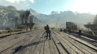A screenshot from Dragon's Dogma 2, showing the player character standing on a wooden bridge, with woodland and mountains in the distance