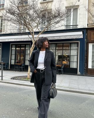 French woman in black tee and blazer.