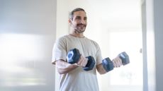 Man exercising with dumbbells at home
