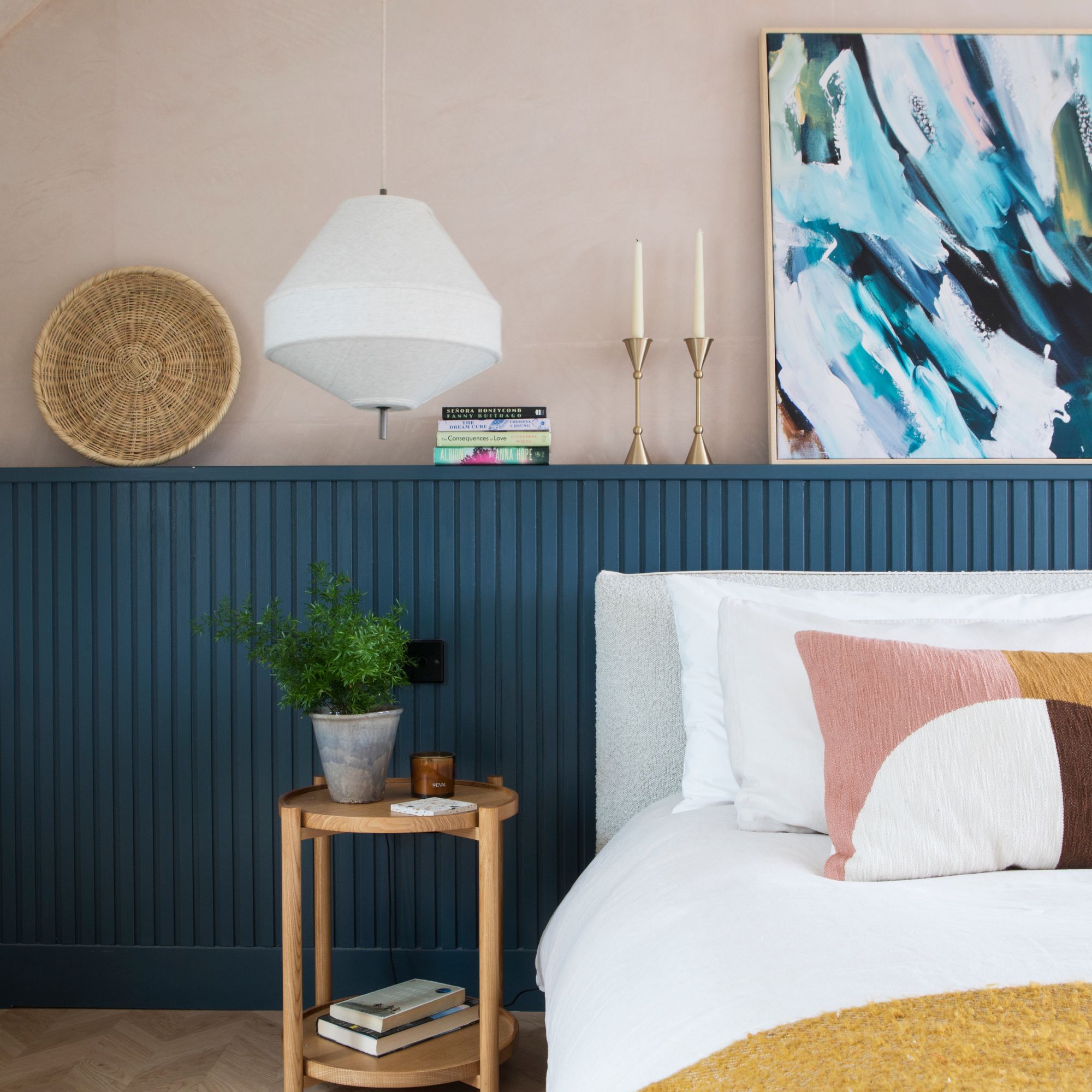 Pink painted bedroom with blue panelling and a bed with white bedding
