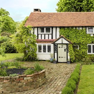 house exterior with white wall and red slate roof and garden area