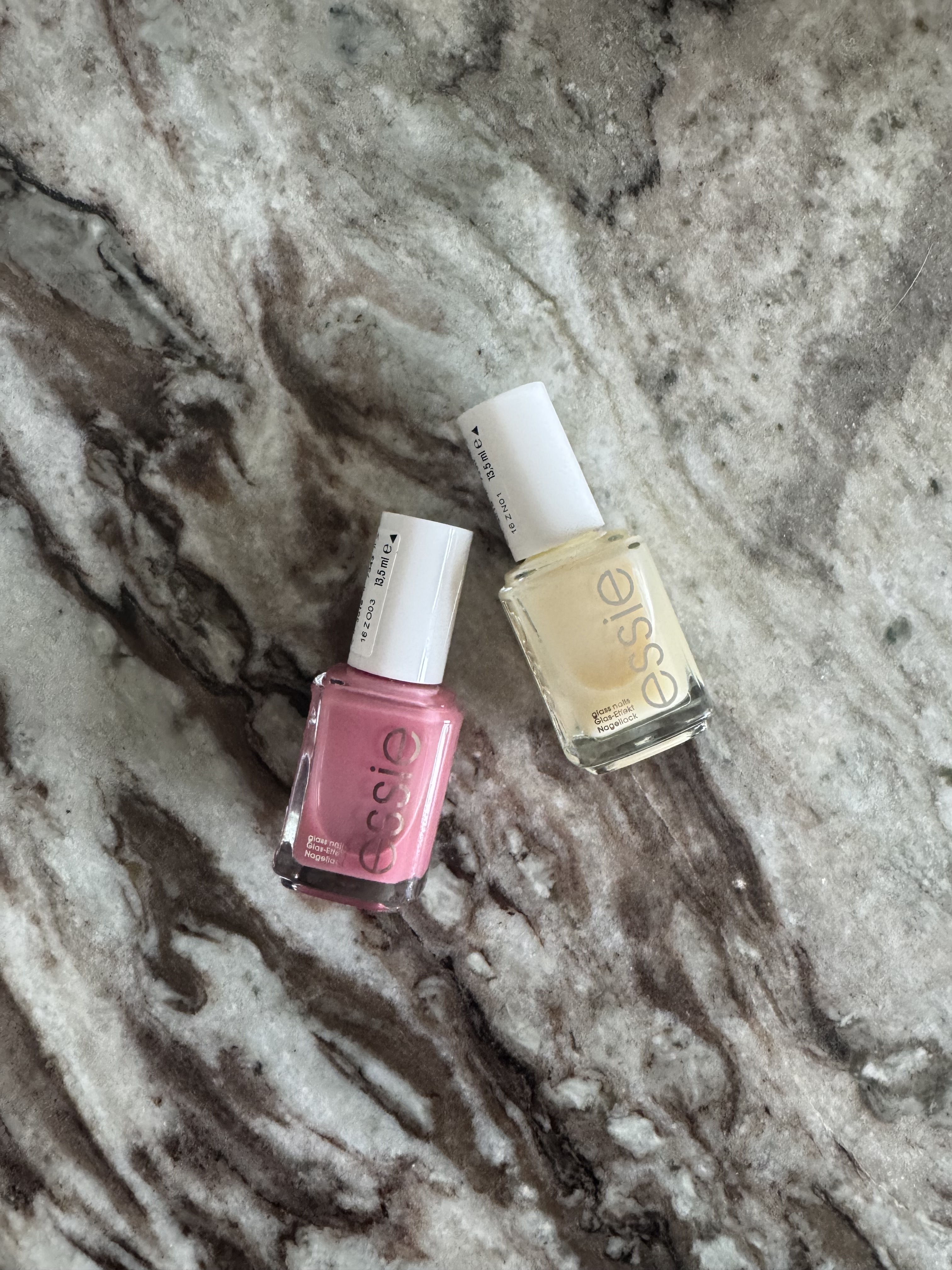 The Essie Glass Nail polishes in shades Crystal Ball and Cin Cin on a marble table